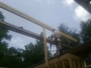Carpenter setting a ridge beam over a new addition frame — Ice Dam Removal by Roofing Brothers in Denver