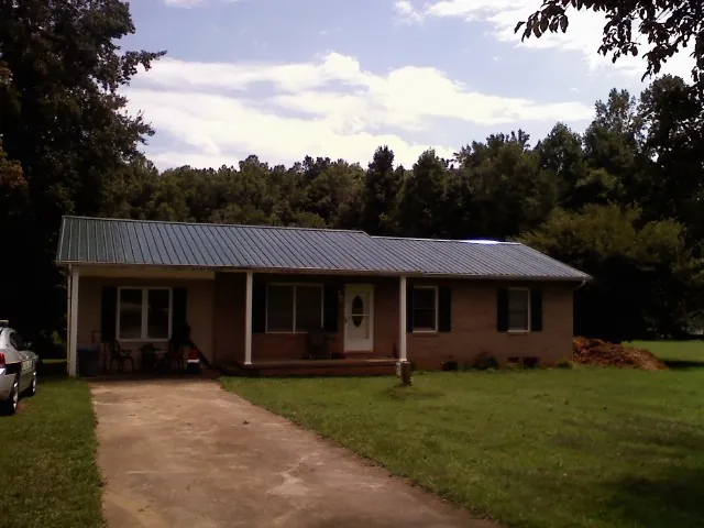 Dark green metal roof on a brick ranch with a covered porch in Denver