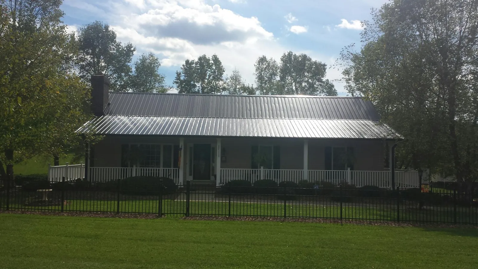 Gray metal roof on a brick ranch with a full width front porch — Gutter Guard Installation work by our crew in Denver